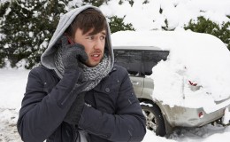 Young man in snow with broken down car